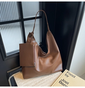 Détail d'un sac cabas en cuir marron avec texture litchi et une petite pochette