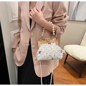 Detail of beaded shell bag with butterfly embroidery, sequins, and pearl handle strap