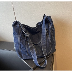 Detail of dark blue denim tote bag with frayed edges and functional side pockets
