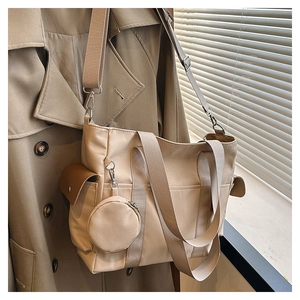 Detail of canvas tote bag with side pockets and a small round coin purse charm