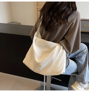 Detail der weißen Cord-Hobo-Tasche am Modell zeigt großes Fassungsvermögen und Faltentextur