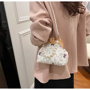 Detail view of a shell-shaped bag with sequin butterflies and wood frame closure