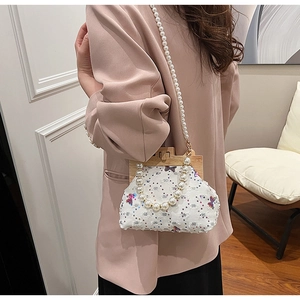 Detail of white sequin shell bag with butterfly embroidery and pearl bead handle