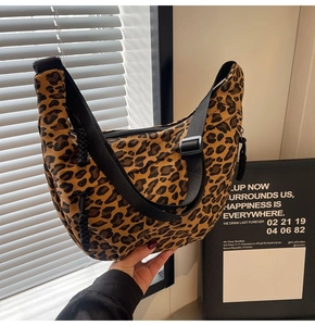 Detail of leopard print crescent bag featuring adjustable black strap and buckle