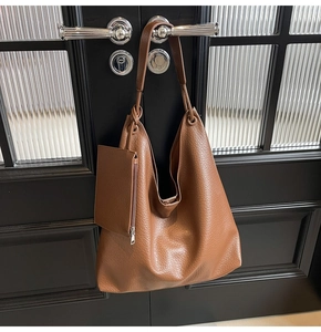 Détail d'un sac hobo en cuir marron avec motif litchi et une petite pochette assortie