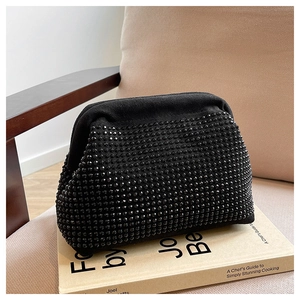 Close-up of black rhinestone evening shell bag placed on a book in a cozy setting