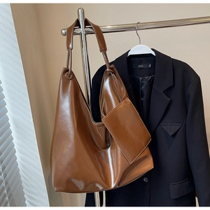 Detail of dark brown hobo bag showing glossy faux leather texture and a small pouch