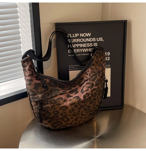 Detail view of the leopard print crescent bag with adjustable strap and woven zipper pull