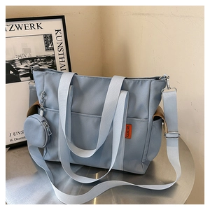Detail of light blue nylon tote bag showing the side brown pocket and mini coin purse