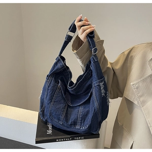Detail of frayed edge denim hobo bag with adjustable wide fabric shoulder strap