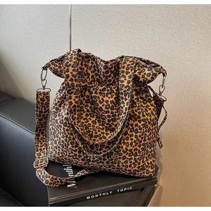 Detail of leopard print canvas bag with wide adjustable strap on a leather chair