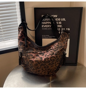 Detail view of the leopard print canvas dumpling bag with textured straps and zipper pockets