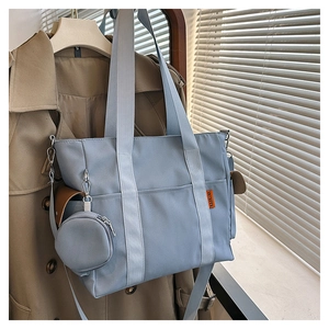Macro detail of fog blue nylon tote bag with round coin purse and orange logo tag