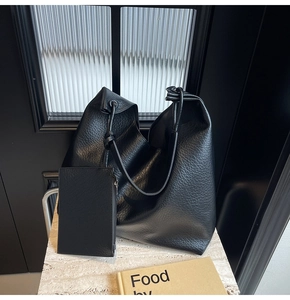 Détail du grand sac hobo noir avec pochette zippée assortie sur surface en marbre