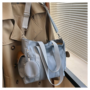 Detail view of light blue nylon tote bag with side pockets and a detachable round coin purse