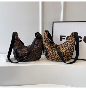 Detail of leopard print canvas crescent bags with adjustable black straps in two color tones