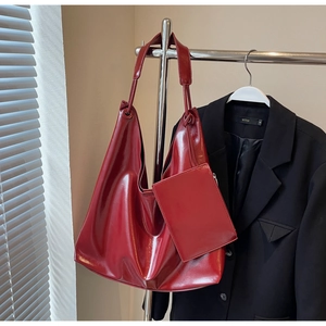 Detail of red glossy hobo bag and matching pouch accessory on a black blazer jacket