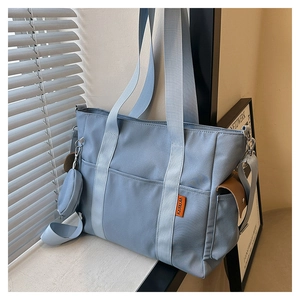 Detail of light blue canvas tote bag with woven handles and small round coin purse