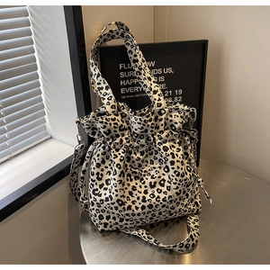 Detail of leopard print canvas bucket bag with drawstring closure on a metal table