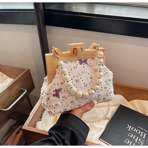 Detail of canvas shell bag featuring sequin butterfly and pearl beaded handle detail