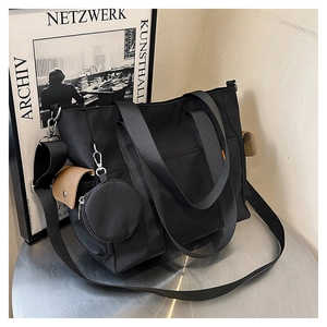Close-up of black nylon tote bag with side pocket, brown flap, and small round coin purse