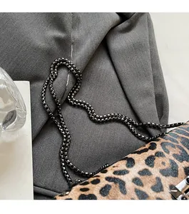 Gros plan d'un sac léopard avec chaîne en métal foncé et détails de clous argentés
