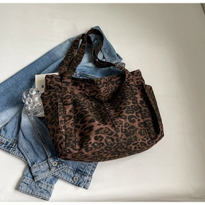 Dettaglio della borsa tote in tela leopardata con tasche laterali e spalline larghe
