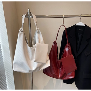 Detail of minimalist hobo tote bags in glossy burgundy and matte white with matching pouches