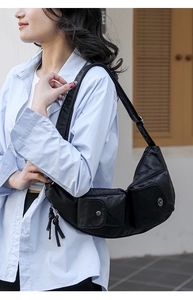 Vue latérale d'un sac bandoulière demi-lune noir avec poches cargo porté par un modèle