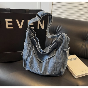 Detail view of washed denim tote bag featuring side pockets with distressed frayed edges