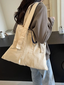 Minimalist large canvas tote bag with orange contrast stitching shown on a shoulder