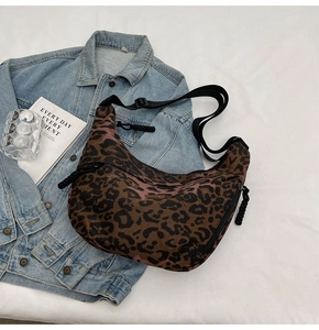 Detailed close-up of leopard print dumpling bag with adjustable strap and cord zipper pull