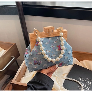 Detail of denim handbag featuring sequin butterflies, wooden frame and pearl handle