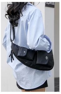 Détail du sac bandoulière noir en demi-lune avec poches utilitaires et longs zips à franges