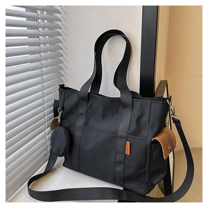 Detail of a black nylon tote bag featuring side pockets and a small round coin purse
