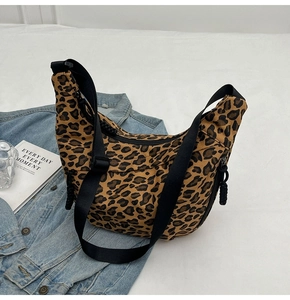 Detail of trendy leopard print canvas crescent bag with a black wide nylon shoulder strap
