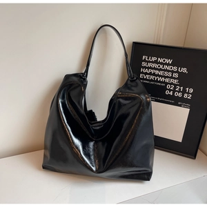Close-up of a large black glossy leather shoulder bag with sleek mirror-like finish