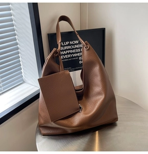Détail d'un grand sac cabas en cuir grainé marron avec une petite pochette assortie
