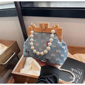 Detail of blue denim seashell bag with pearly handle, butterfly sequins and wooden frame