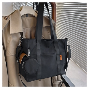 Detail of black canvas tote bag with adjustable shoulder strap and round coin purse pouch