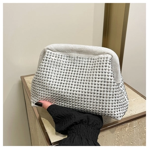 Detailed view of silver shell-shaped evening bag encrusted with sparkling rhinestones