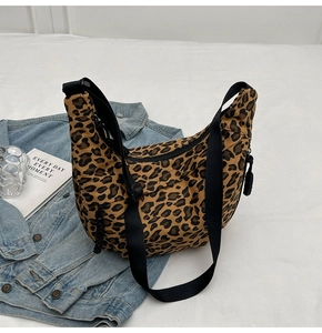 Macro detail of leopard print crescent bag with adjustable black strap on white background