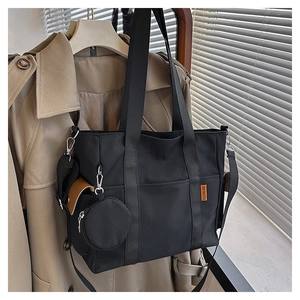 Black canvas tote bag detail featuring orange brand tag and detachable coin purse accessory