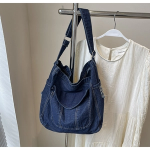 Detailed macro of vintage indigo denim tote bag featuring contrast stitching and cargo pockets