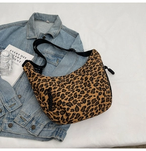 Detail of leopard print canvas crescent bag with adjustable wide shoulder strap on denim