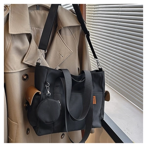Detail of black nylon tote bag featuring a detachable shoulder strap and round coin purse