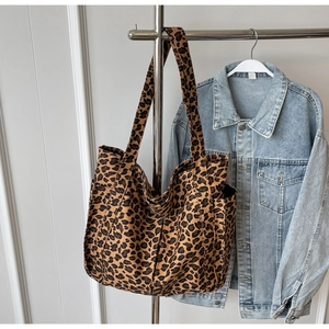 Dettaglio di una borsa tote in tela leopardata appesa accanto a una giacca di jeans