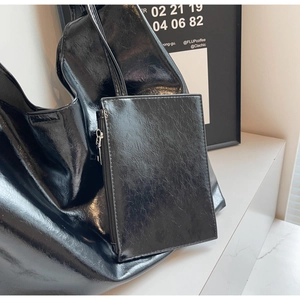 Close-up of shiny black faux leather tote bag with matching rectangular zipper pouch