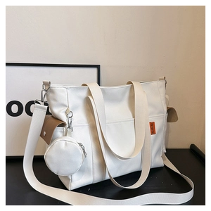 Detail view of off-white canvas tote bag with brown buckle pocket and round coin purse