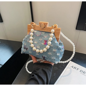 Detail of denim shell bag with sequined butterfly embroidery and wooden clasp